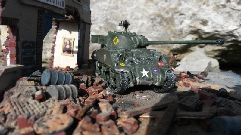 Ein britischer Sherman Firefly durchquert eine von der Wehrmacht bereits verlassene deutsche Stadt