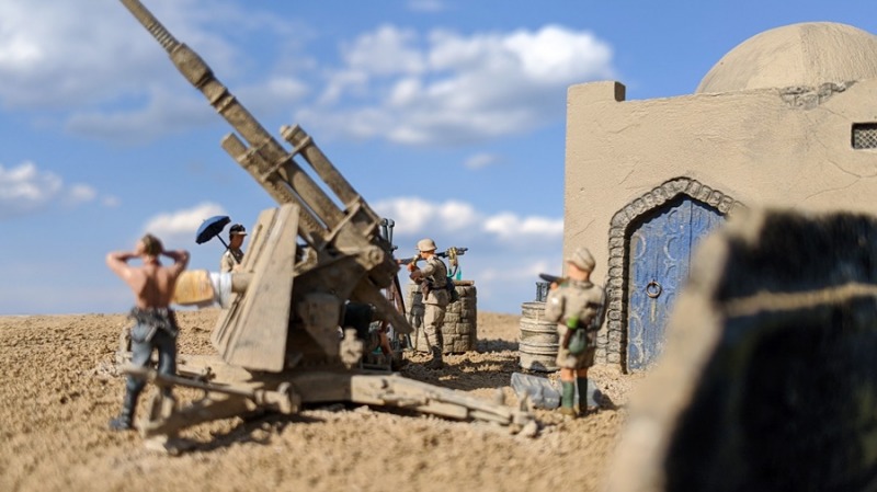 Währenddessen sorgt einer der Flak-Helfer für Munitionsnachschub und ein weiterer trocknet seine schweißnasse Uniform in der Wüstensonne