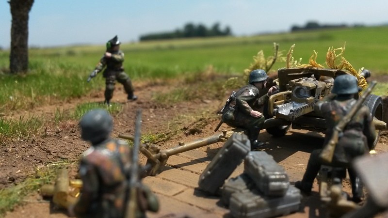 Während der rechte Soldat die neuen Feindpositionen erspäht, richtet der Richtschütze die Kanone bereits auf die neuen Ziele aus.